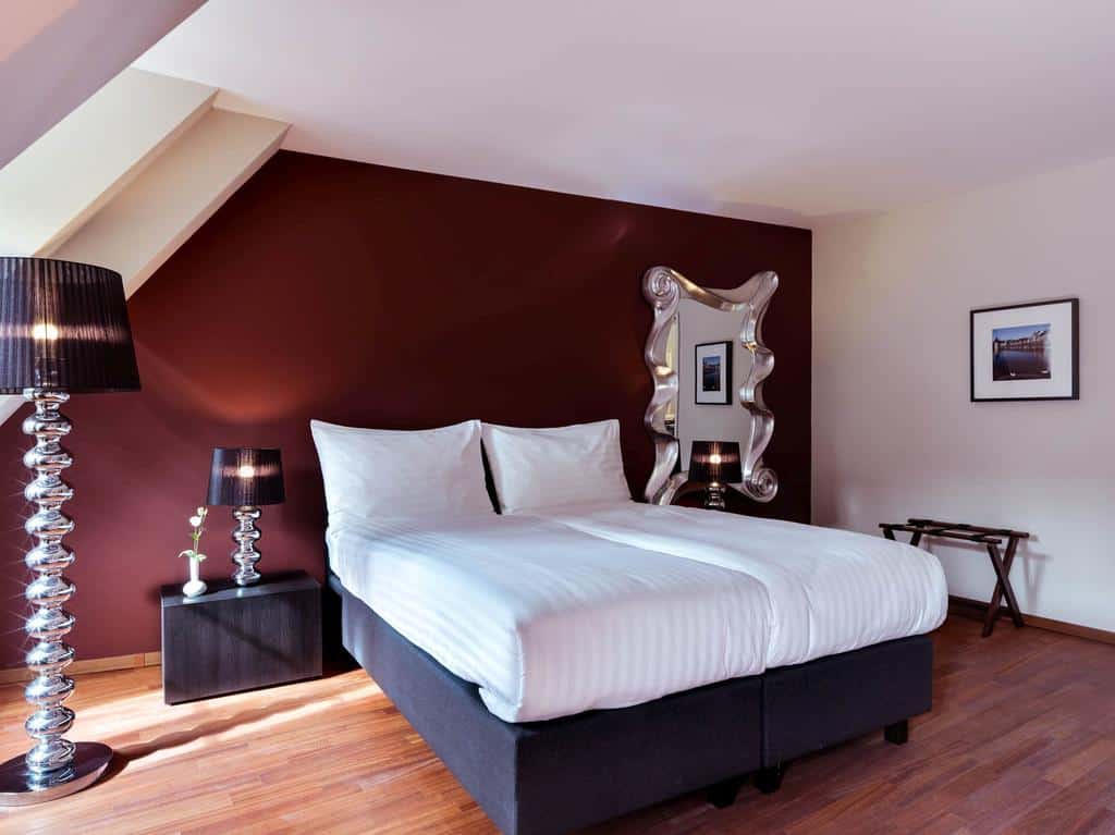 Modern hotel room with white bedding and dark red wall