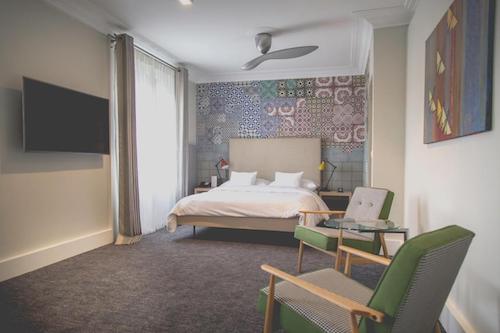 Modern hotel room with patterned wall and green chairs