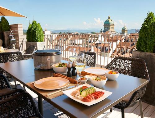 Rooftop terrace with lunch setup and city views, including the Bern Parliament dome in the background.