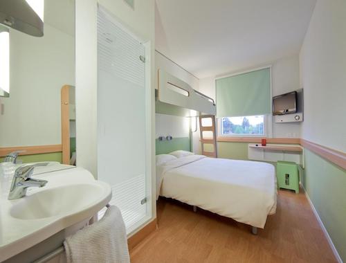 Compact hotel room with a bunk bed setup and a small desk at Ibis Budget in Lugano.