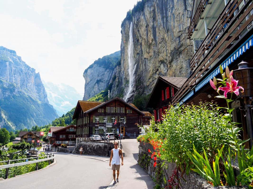 Tourist walking near Staubbach Falls and wooden houses