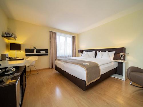 Modern hotel room with wooden flooring and a large comfortable bed