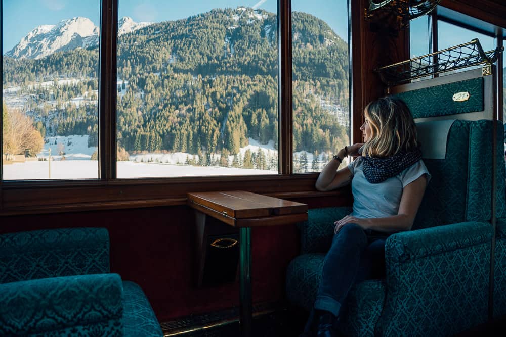 Woman on scenic train ride watching snowy Swiss Alps