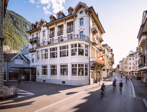 Street view of a charming white hotel building with cyclists passing by